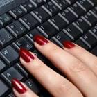 A person’s fingers with red painted nails on a black keyboard