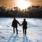 Two people walking and holding hands in the snow