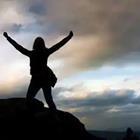 A person on top of a mountain with their arms raised