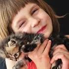 A girl holding a cat to her face and smiling