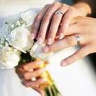 Two people holidng hands with rings on their fingers and white flowers being held