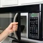 A person with their hand on a microwave door handle