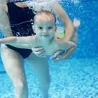 A woman holding a child as it swims