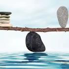 A black rock balancing a piece of wood with two objects on it