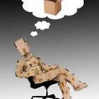 A person in cardboard sitting on a chair thinking of something