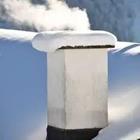 A chimney with snow on top of it and smoke coming out