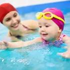 An adult and a child in a pool with red bathing-caps on.