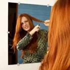 Red haired woman cutting hair in mirror