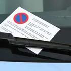 A white note with a symbol on it on the windshield of a car