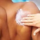 A person rubbing white stuff on to someone’s back