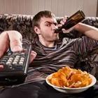 A person drinking on the couch with a bowl of food