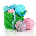 A green basket with different color wool inside of the basket and outside the basket
